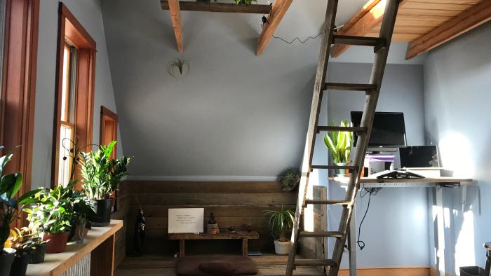 A bedroom transformed, with plants, meditation space and rustic, barn wood standing desk
