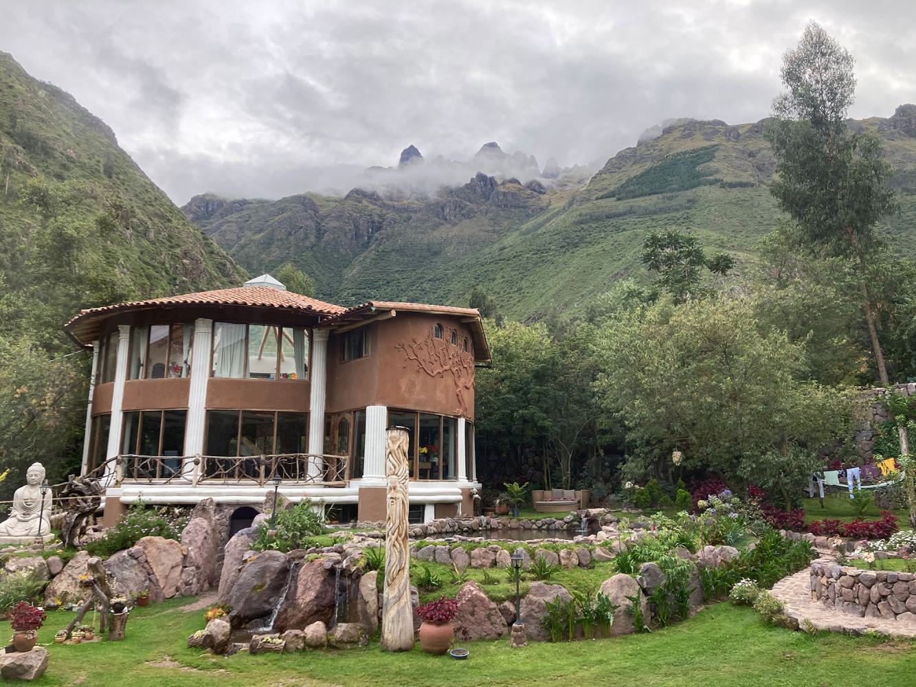 A circular retreat center nestled in a valley beneath a towering Peruvian mountain range.