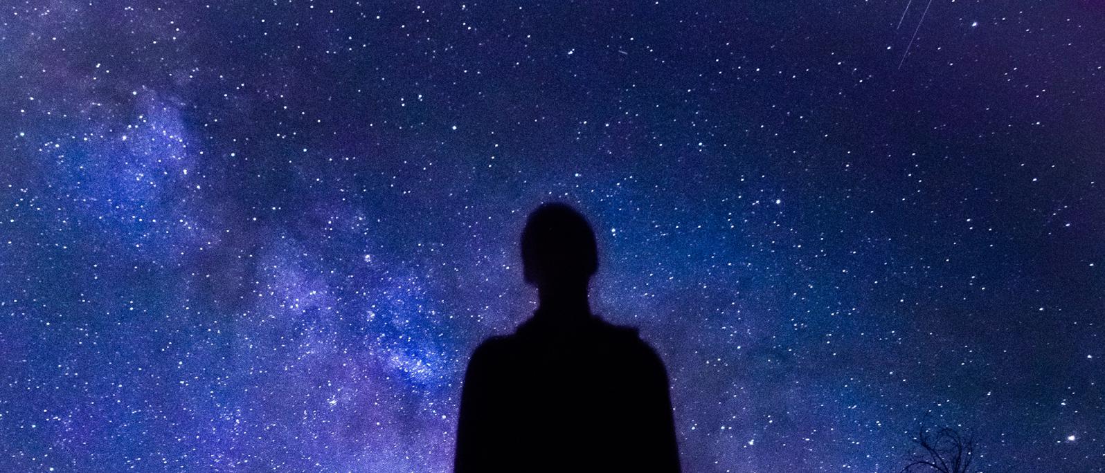 Silhouette of a young man looking at the starry sky